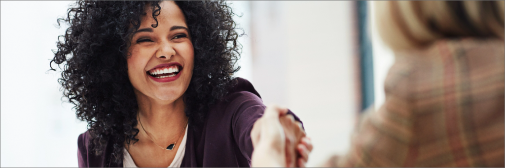 Woman smiling and shaking another person's hand