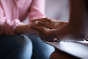 client and therapist clasp hands in a cognitive-behavioral therapy program